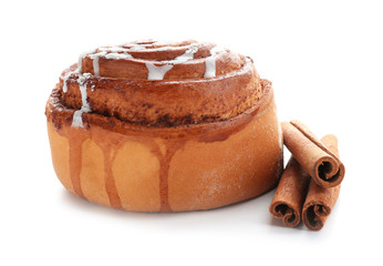 Tasty bun with icing and cinnamon sticks on white background