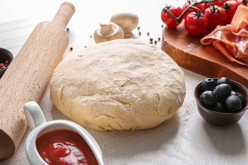 Raw dough with ingredients for pizza on table