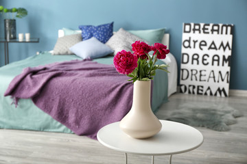Vase with beautiful flowers on table in bedroom