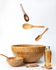 Wooden bowl spoon utensils oil bottle on white background elevated flying floating