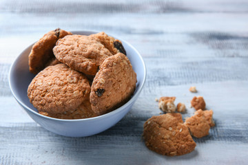 Bowl with delicious oatmeal cookies on wooden background