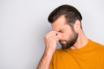 Close up portrait of stressed sick sad upset bearded guy with stylish haircut touching nose-bridge isolated on gray background copy-space