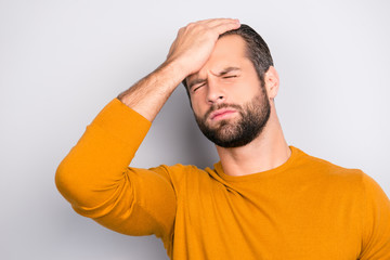 Close up portrait of frustrated unhappy suffering from terrible migraine bearded man touching his forehead with closed eyes isolated on gray background