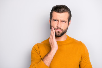 Close up portrait of nervous unhappy troubled handsome bearded man touching his cheek he has...