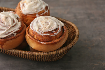 Basket with delicious cinnamon buns on grey background
