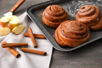 Tray with delicious cinnamon buns on table, closeup