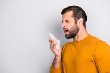Profile side view half-faced portrait of sad upset unhappy tired ill sick bearded handsome man wearing yellow sweater using paper tissue to blow nose out isolated on gray background copy-space