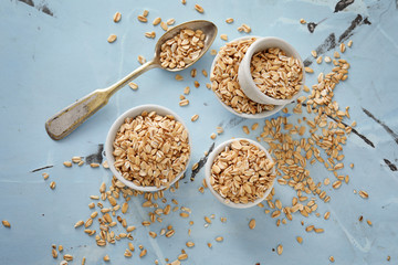Bowls with raw oatmeal on color background