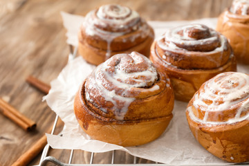Cooling rack with tasty cinnamon buns on wooden table, closeup