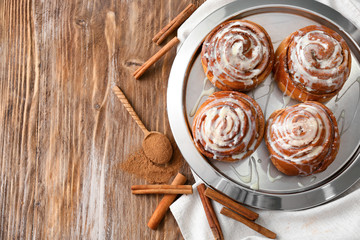 Plate with tasty cinnamon buns on wooden table