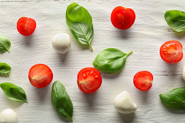 Composition with fresh basil leaves, tomatoes and mozzarella on wooden background