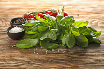 Fresh basil with spices on wooden table