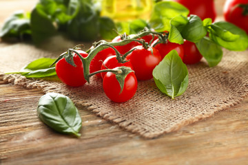 Fresh basil with tomatoes on wooden table