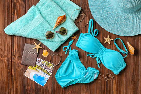 Composition with passport, bikini and beach accessories on wooden background