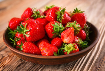 Plate with ripe red strawberries on wooden table