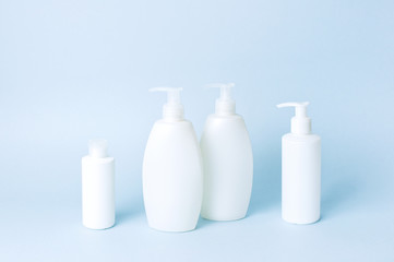 Cosmetic bottle containers on a blue minimalistic background flat lay. Blank label for branding mock-up. Natural beauty product concept.