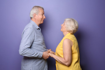 Happy senior couple on color background