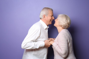 Happy senior couple on color background
