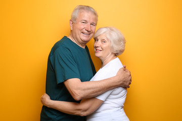Happy senior couple on color background