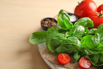 Stand with fresh basil, spices and tomatoes on light background