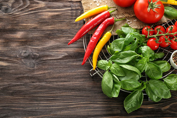 Fresh basil, chili peppers and tomatoes on wooden background