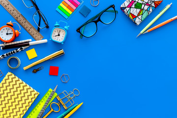 Education concept. Stationery frame with glasses and notebook on blue background top view copy space