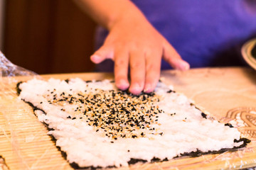 mom and daughter making at home Japanese sushi rolls.