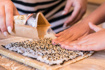 mom and daughter making at home Japanese sushi rolls.
