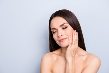 Mature gorgeous sensual woman with maquillage, close eyes, holding hand on cheek, having pleasure, enjoying result after lotion cream mask procedure isolated on grey background, copy space