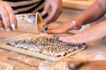 mom and daughter making at home Japanese sushi rolls.