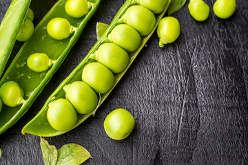 Opened pods of peas on black, macro