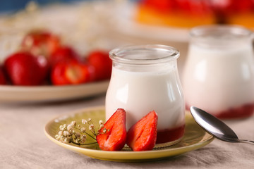 Glass jar with tasty yogurt and strawberries on table