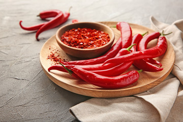 Plate with fresh and granulated chili pepper on light background