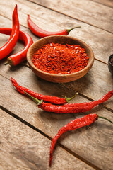 Dry granulated and fresh chili pepper on wooden background