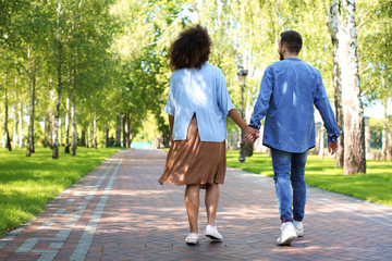 Young loving interracial couple walking in park on spring day