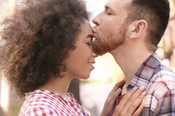 Young man kissing his beautiful African-American girlfriend outdoors