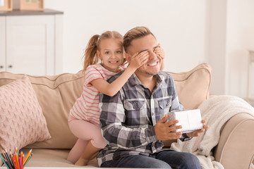 Cute little girl greeting her daddy with Father's Day at home