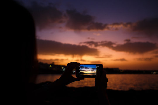  girl takes pictures of a beautiful sunset