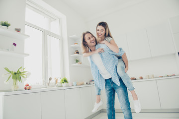 Low angle view portrait of cheerful trendy partners enjoying free time together having pleasure, handsome man carrying on back lover. Affection delight feelings concept