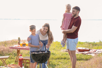 Family cooking tasty food on barbecue grill outdoors. Summer picnic