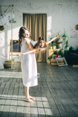 Mother is swinging daughter and smiling indoors. Happy to be together. Having fun. Vertical orientation