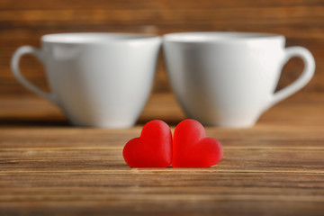 Heart-shaped jelly candies with cups on wooden table