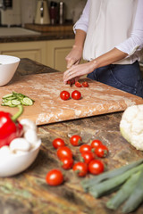 Beautiful young brunette woman in casual outfit cooking in the kitchen in her home. Luxury rich interior