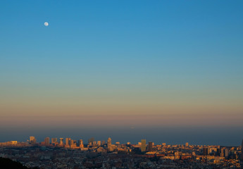 Full moon under Barcelona cityscape.