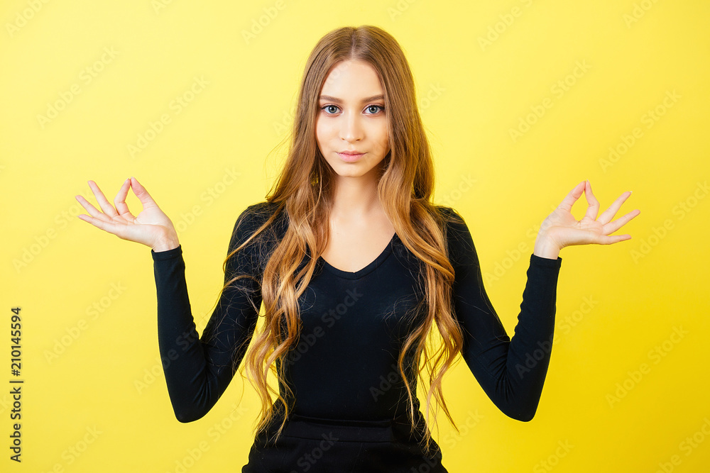 Wall mural portrait of a young attractive woman with long hair practicing yoga and meditating in the studio on 