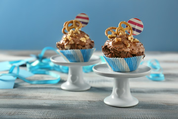 Dessert stands with delicious cupcakes on table against color background