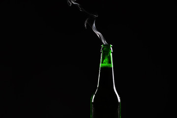 Glass bottle of cold beer on dark background