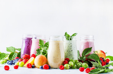 Healthy and useful colorful berry smoothies with yogurt, fresh fruit and berries on a gray background, selective focus