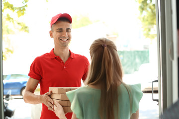 Young man giving pizza boxes to woman at doorway. Food delivery service