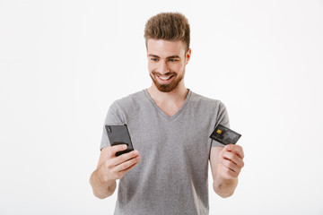 Cheerful young man holding credit card using mobile phone.